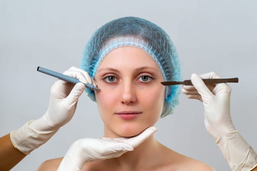 Young woman preparing for plastic surgery in cosmetic clinic. Head of female with hands in gloves with equpment for procedure. Specialists planning rejuvenation.