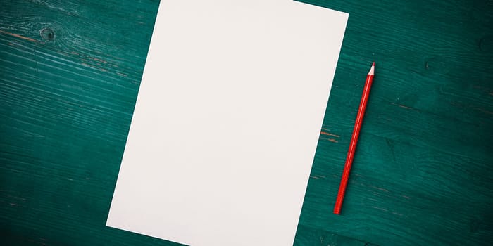 A blank white sheet and pencil for drawing on a wooden background with space for copying and lettering. Layout, mockup free space.