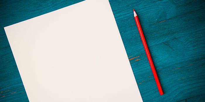 A blank white sheet and pencil for drawing on a wooden background with space for copying and lettering. Layout, mockup free space.
