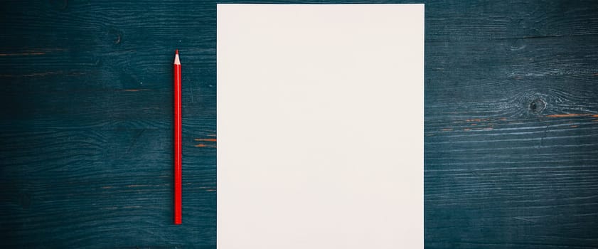 A blank white sheet and pencil for drawing on a wooden background with space for copying and lettering. Layout, mockup free space.