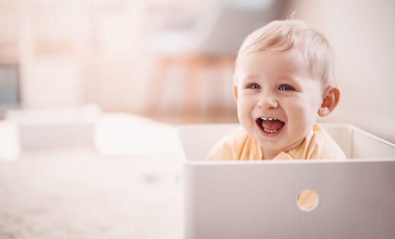 Cute boy sitting in the white plastic box. Baby laughing. Concept of the family and mother's love.