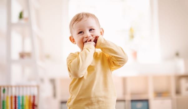 Cute boy standing in the white room. Playful funny baby looking at the camera. Concept of the family and mother's love.