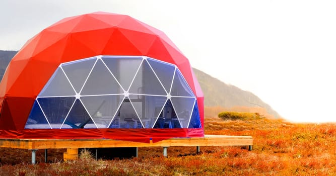 The Red geo-dome tent on Kamchatka peninsula. Cozy, camping, glamping, holiday, vacation lifestyle concept. Outdoors cabin, scenic background
