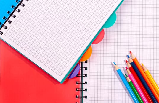 The colored notebooks and pencils. Pencils on an empty notebook