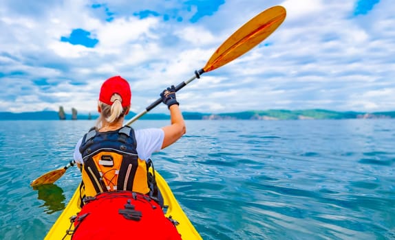 The Girl on single kayak or canoe swims at Avacha bay in Kamchatka peninsula