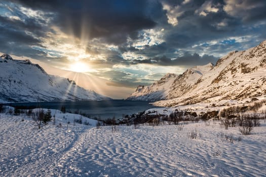 Frozen mountain lake landscape on a mountain near tromso, norway during sunrise with cloudy sky