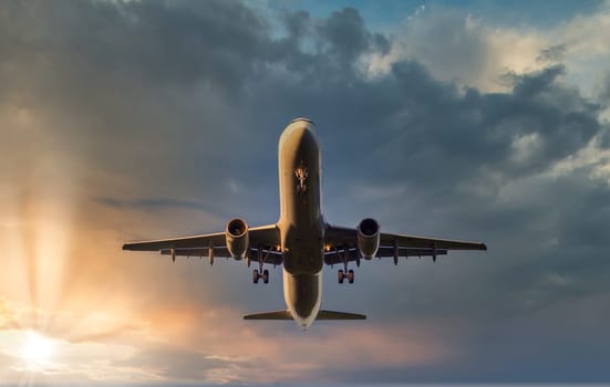 Airplane landing during sunset at airport with clouds in background, view from low angle