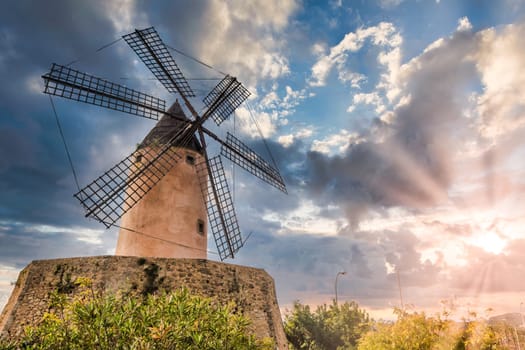 Old windmill near palma in mallorca, majorca during sunrise with clouds, low angle view