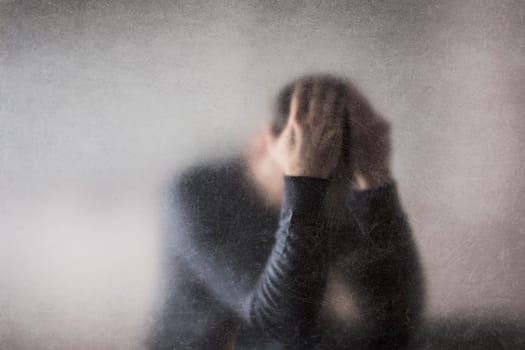 Depression. Broken man behind a dusty scratched glass.