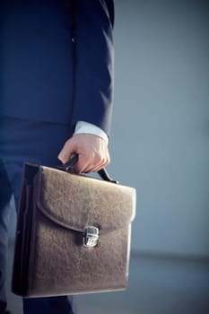 Vertical cropped image of a businessperson carrying a leather briefcase isolated on grey