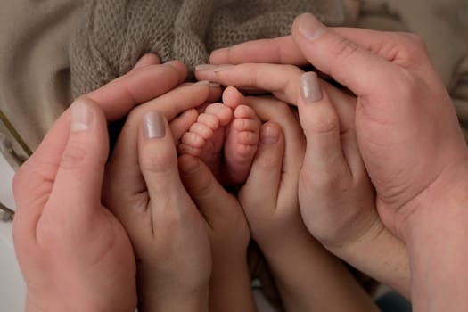 hands of parents and children. the legs of the newborn in the ha