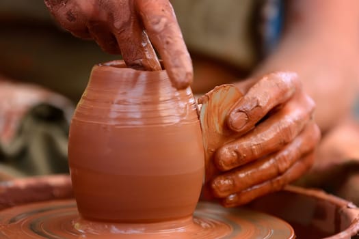 Hands of a potter. Potter making ceramic pot on the pottery wheel