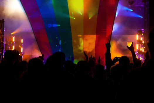 Pride community at a parade with hands raised and the LGBT flag - symbol of love and tolerance