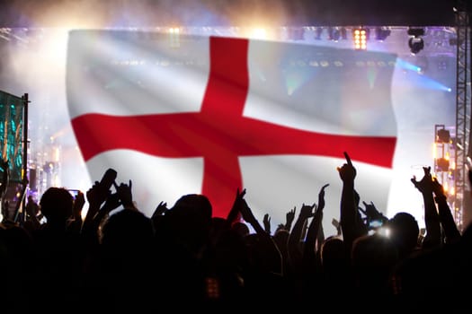 Soccer fans supporting England - crowd celebrating in stadium with raised hands against England flag