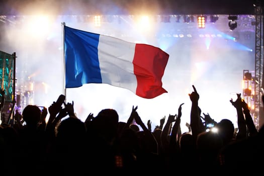 Soccer fans supporting France - crowd celebrating in stadium with raised hands against french flag