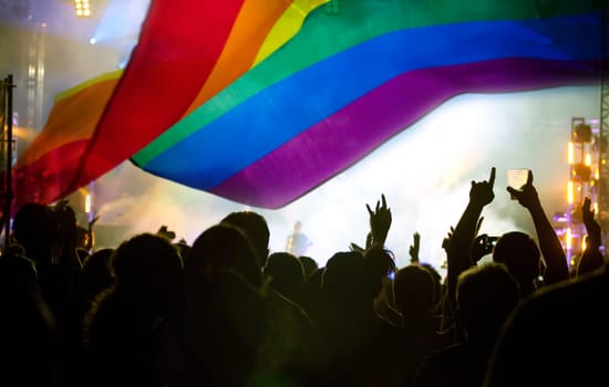Pride community at a parade with hands raised and the LGBT flag - symbol of love and tolerance