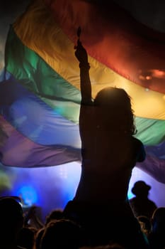 Pride community at a parade with hands raised and the LGBT flag - symbol of love and tolerance