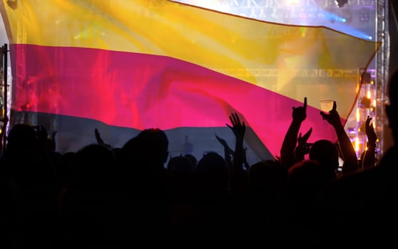 Soccer fans supporting Germany - crowd celebrating in stadium with raised hands against german flag