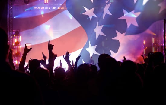 Crowd of people celebrating Independence Day. United States of America USA flag with fireworks background for 4th of July.