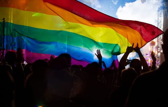 Pride community at a parade with hands raised and the LGBT flag - symbol of love and tolerance