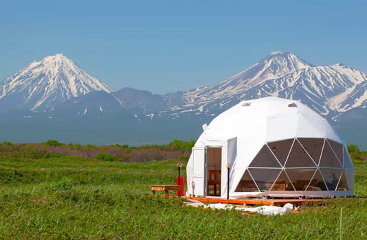The Glamping house in summer and volcano, rural landscape, tent houses in Kamchatka peninsula. Selective focus.