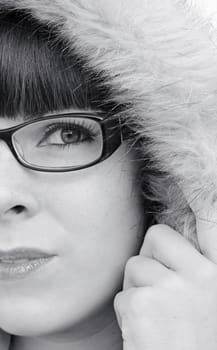 The face of a young woman with glasses and fur hood