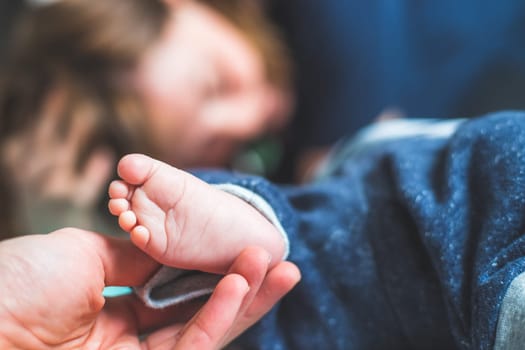 Close up of mother’s hands, holding newborn baby feet.