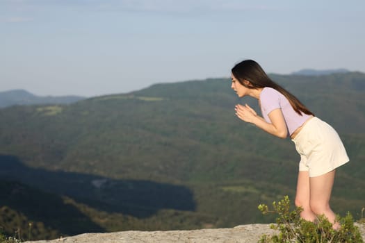 Scared asian woman looking down on a mountain cliff