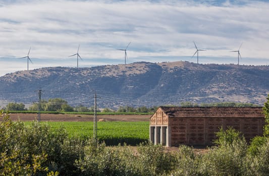 Tobacco drying house with Electric wind turbines at bottom. Carcaboso countryside. Caceres, Extremadura, Spain