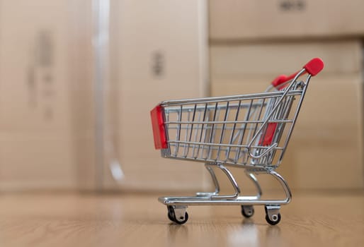 Online-Shopping and parcel service concept: Miniature shopping cart and cardboard boxes
