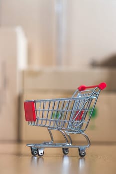 Online-Shopping and parcel service concept: Miniature shopping cart and cardboard boxes