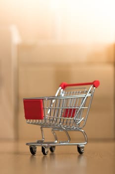 Online-Shopping and parcel service concept: Miniature shopping cart and cardboard boxes