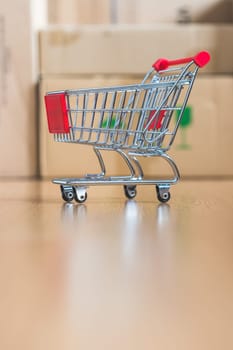 Online-Shopping and parcel service concept: Miniature shopping cart and cardboard boxes