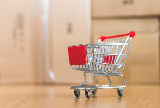 Online-Shopping and parcel service concept: Miniature shopping cart and cardboard boxes