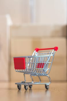 Online-Shopping and parcel service concept: Miniature shopping cart and cardboard boxes