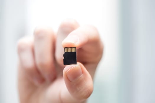 Young man is holding a tiny memory card in his hand, text space
