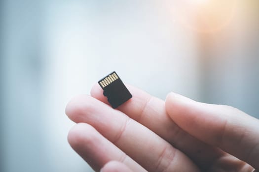 Young man is holding a tiny memory card in his hand, text space