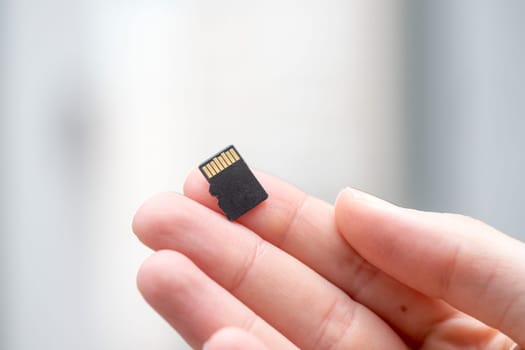 Young man is holding a tiny memory card in his hand, text space