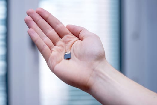 Young man is holding a tiny memory card in his hand, text space