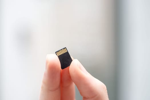 Young man is holding a tiny memory card in his hand, text space