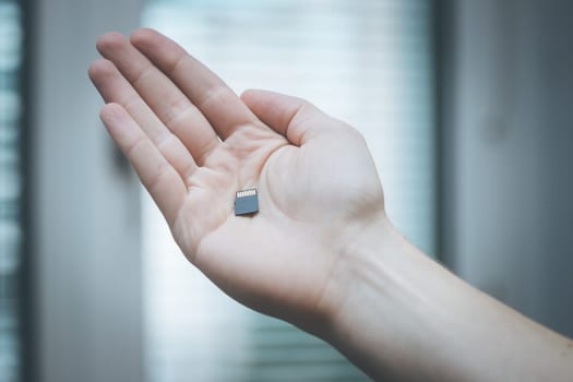 Young man is holding a tiny memory card in his hand, text space