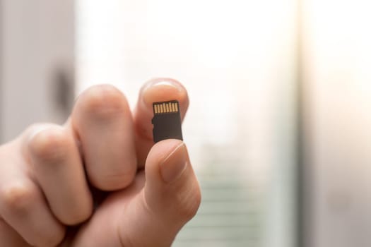Young man is holding a tiny memory card in his hand, text space