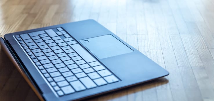 Cutout of a modern laptop keyboard on the wooden floor with text space