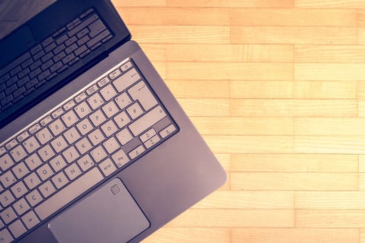 Cutout of a modern laptop keyboard on the wooden floor with text space