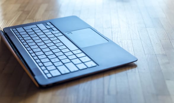 Cutout of a modern laptop keyboard on the wooden floor with text space