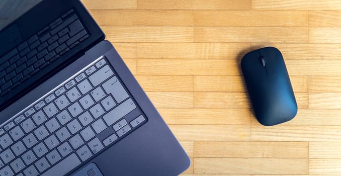 Cutout of a modern laptop keyboard and mouse on the wooden floor with text space