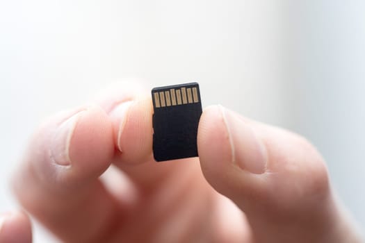Young man is holding a tiny memory card in his hand, text space