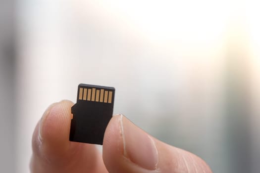 Young man is holding a tiny memory card in his hand, text space