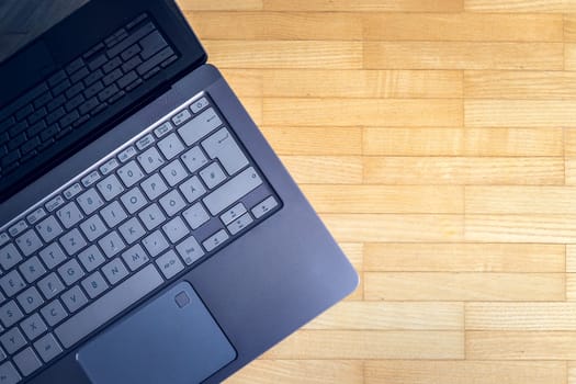 Cutout of a modern laptop keyboard on the wooden floor with text space