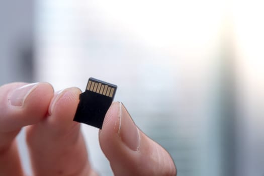 Young man is holding a tiny memory card in his hand, text space